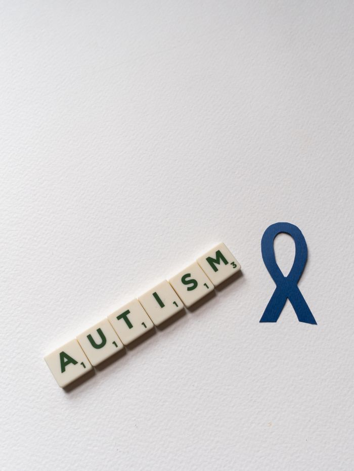 Conceptual image of autism awareness with blue ribbon and letter tiles spelling autism.